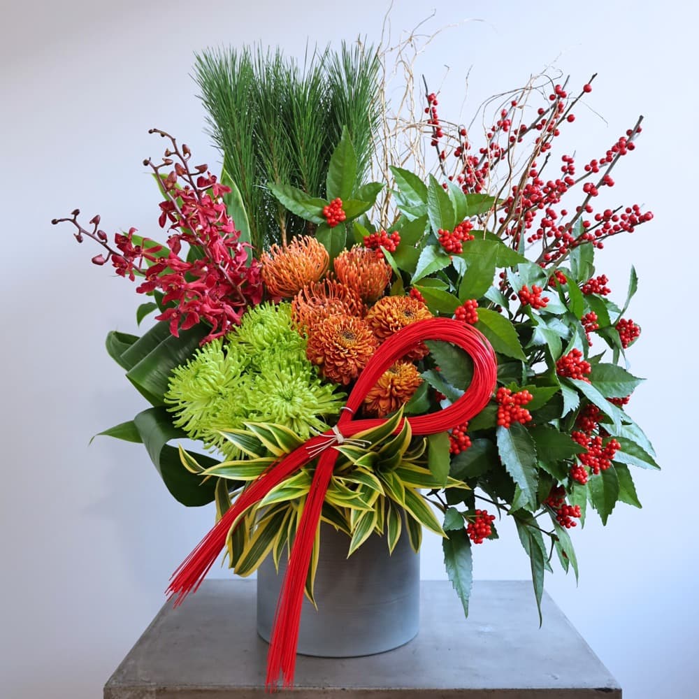 赤い実の枝と橙色の花、紅白の水引を合わせたアーティフィシャルフラワーの迎春アレンジメント